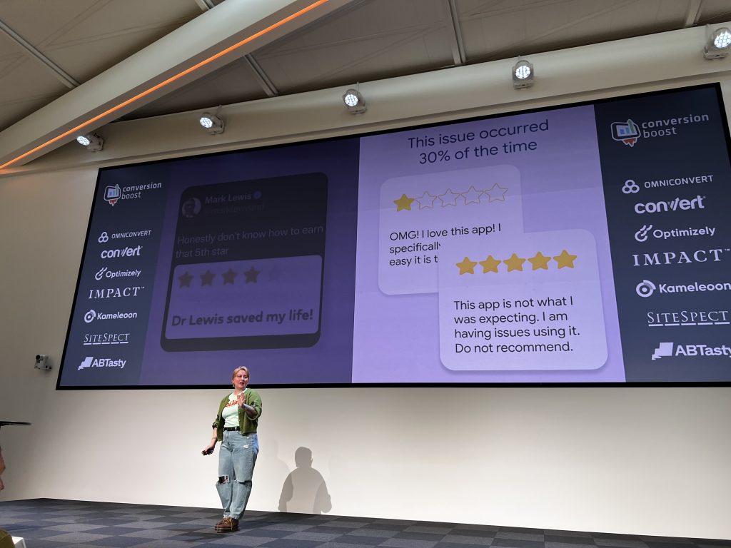 Juliana Jackson stands on stage at Cboost, presenting a slide that displays real customer feedback as part of her talk on leveraging user insights.