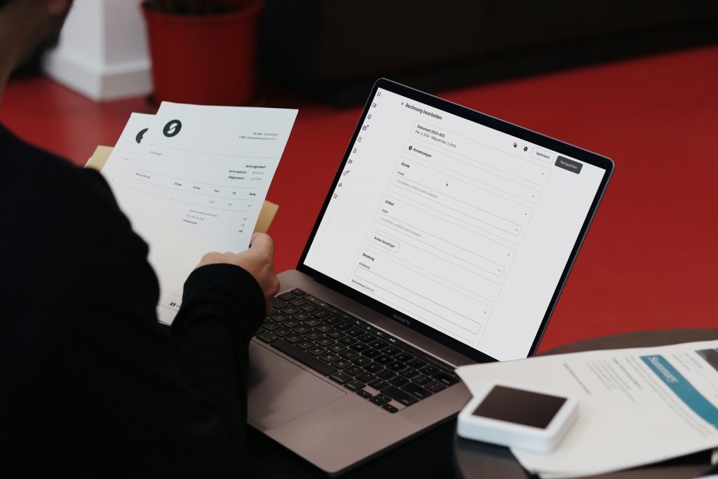 A laptop and a person looking at recruiting papers.
