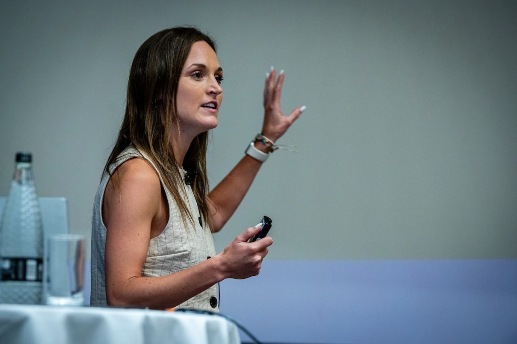 Sadie Minors stands on stage delivering her talk at the TLC Mentorship Summit, Experimentation Elite 2025.
